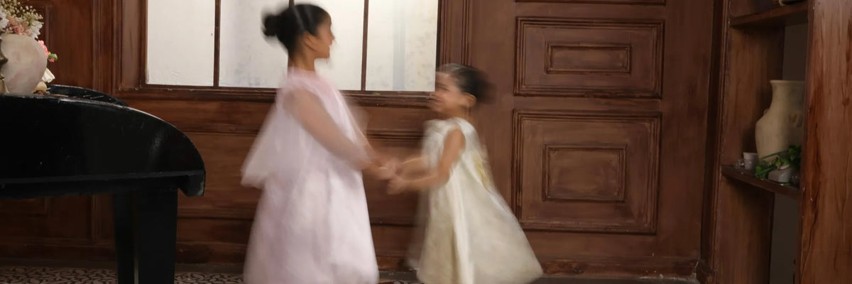 Two girls in Todlem blush pink and ivory occasion dresses dancing together, Special Occasion collection for weddings and Eid.